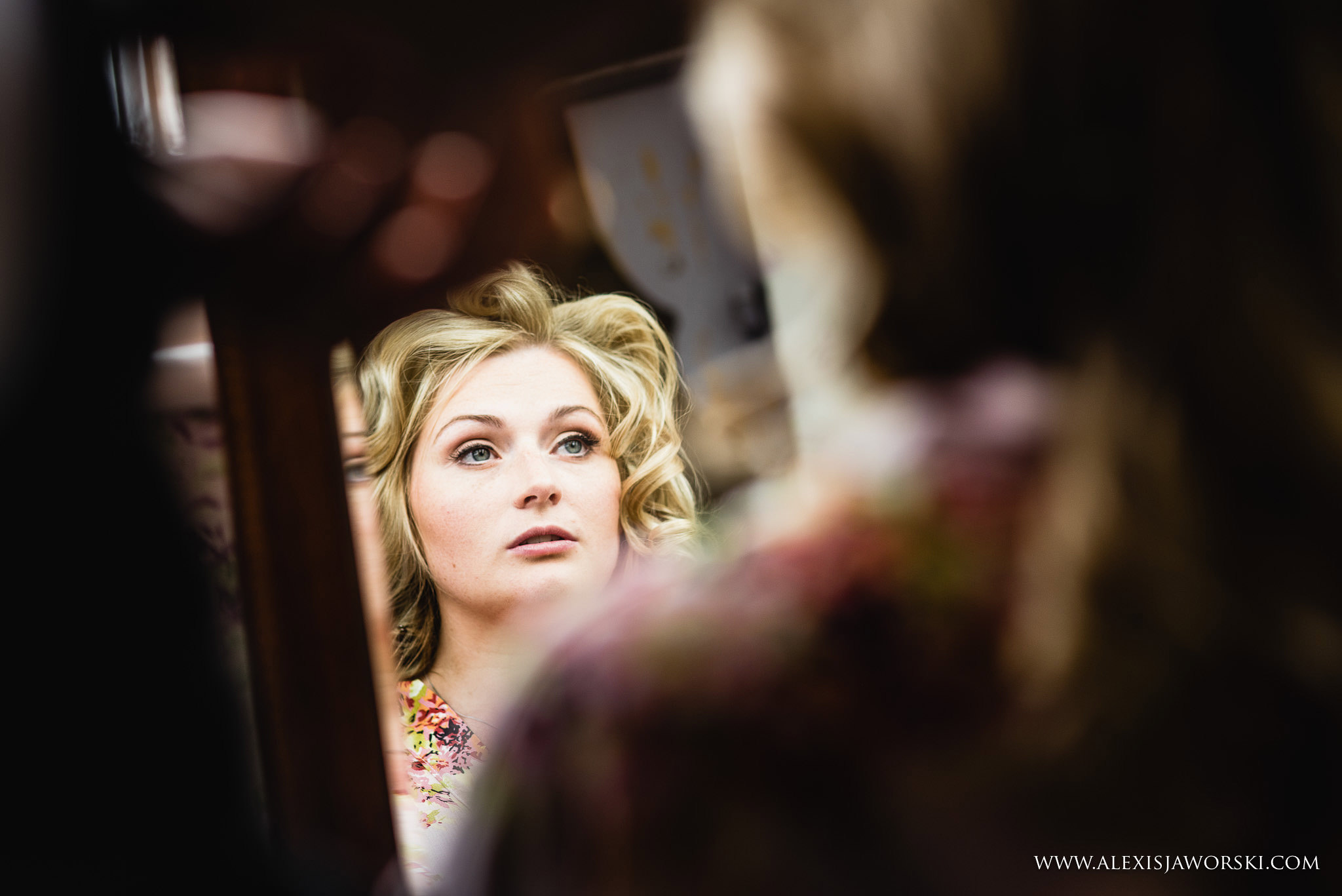 Bride looking into mirror as she gets ready
